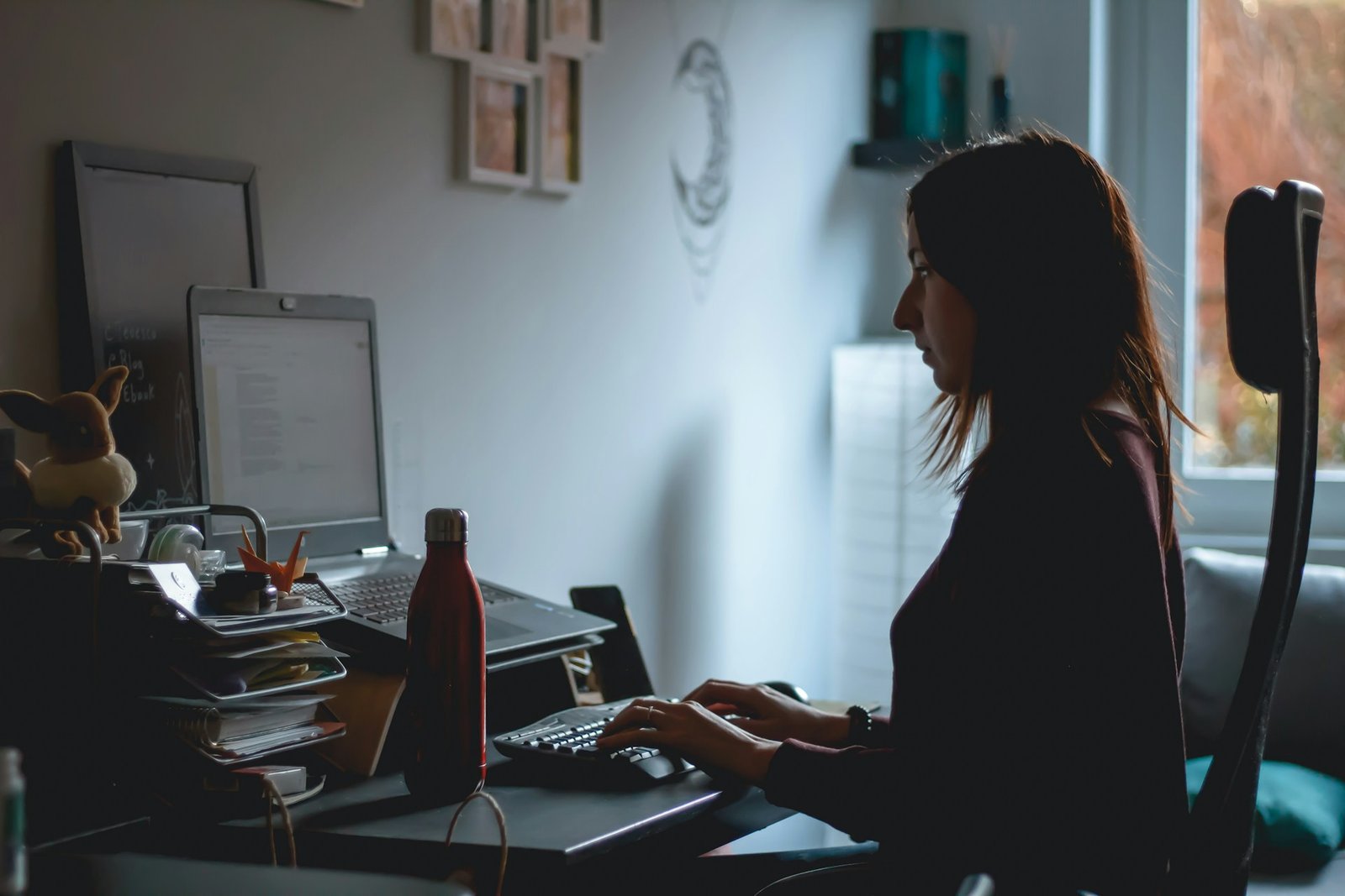 Pessoa trabalhando em home office com postura correta e ambiente ergonômico para prevenir dores nas costas